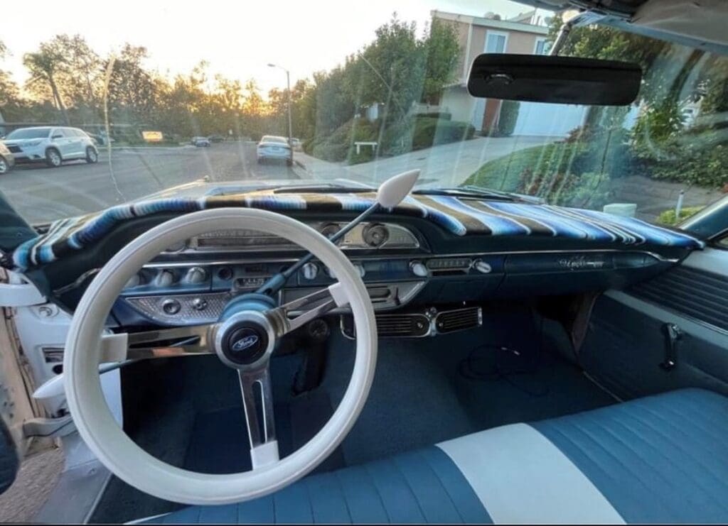 Vintage car interior with a large white steering wheel and classic dashboard.