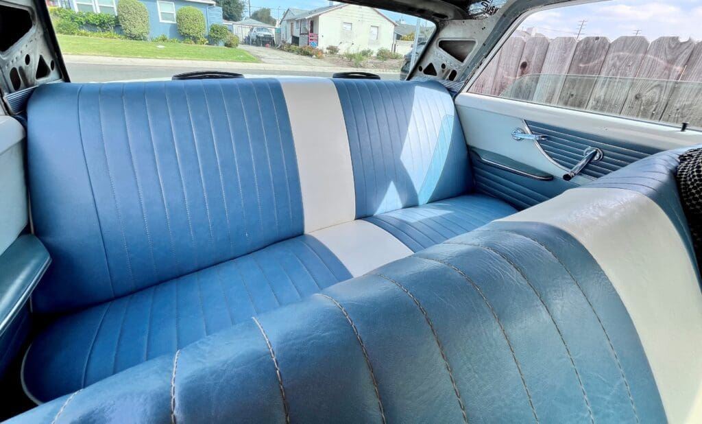 Blue and white vintage car interior with bench seats.