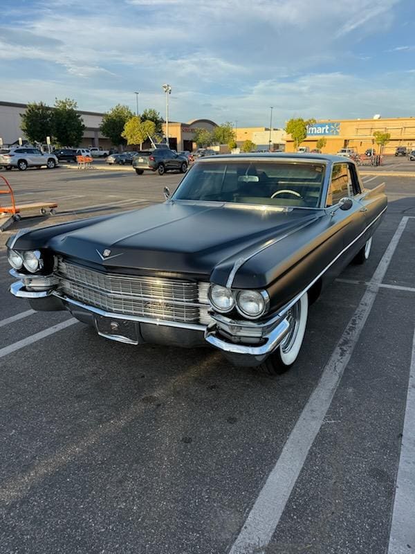 Classic black vintage car parked in a lot on a sunny day.