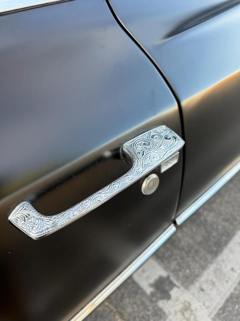 Close-up of a car door handle covered in tape with handwritten markings.