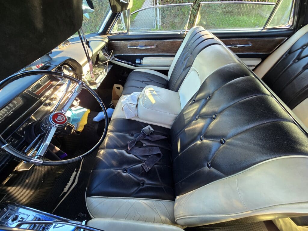 Interior of a vintage car with black and white leather seats and classic dashboard.