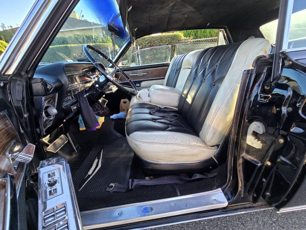 Interior view of a classic car with black and white seats and vintage dashboard.