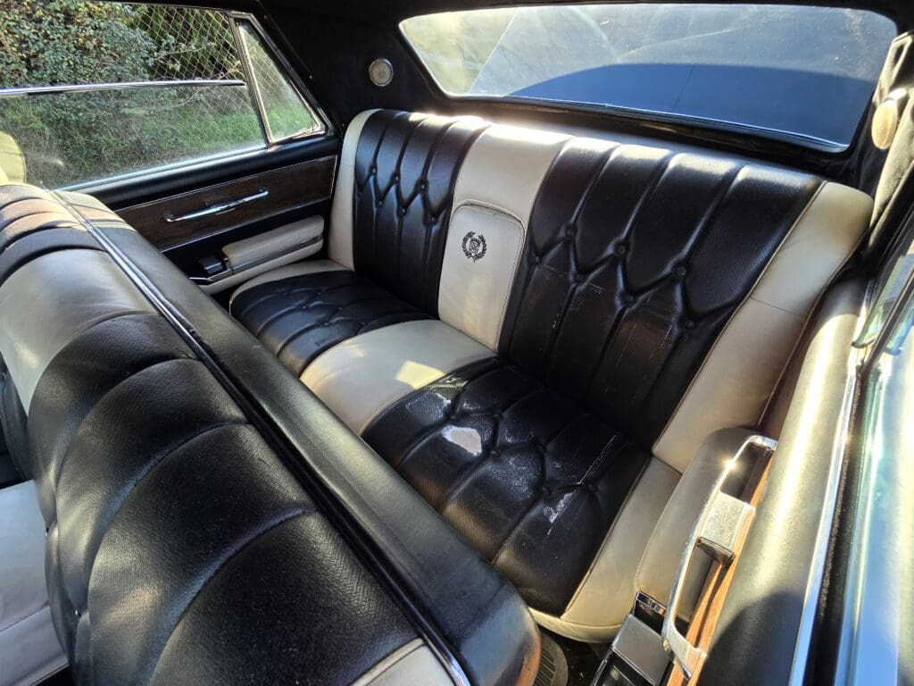 Vintage car's black and cream leather interior with elegant button tufting.