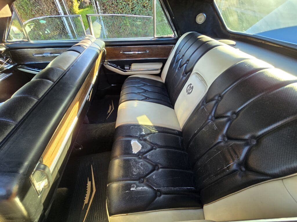 Vintage car interior with black and white tufted leather seats.