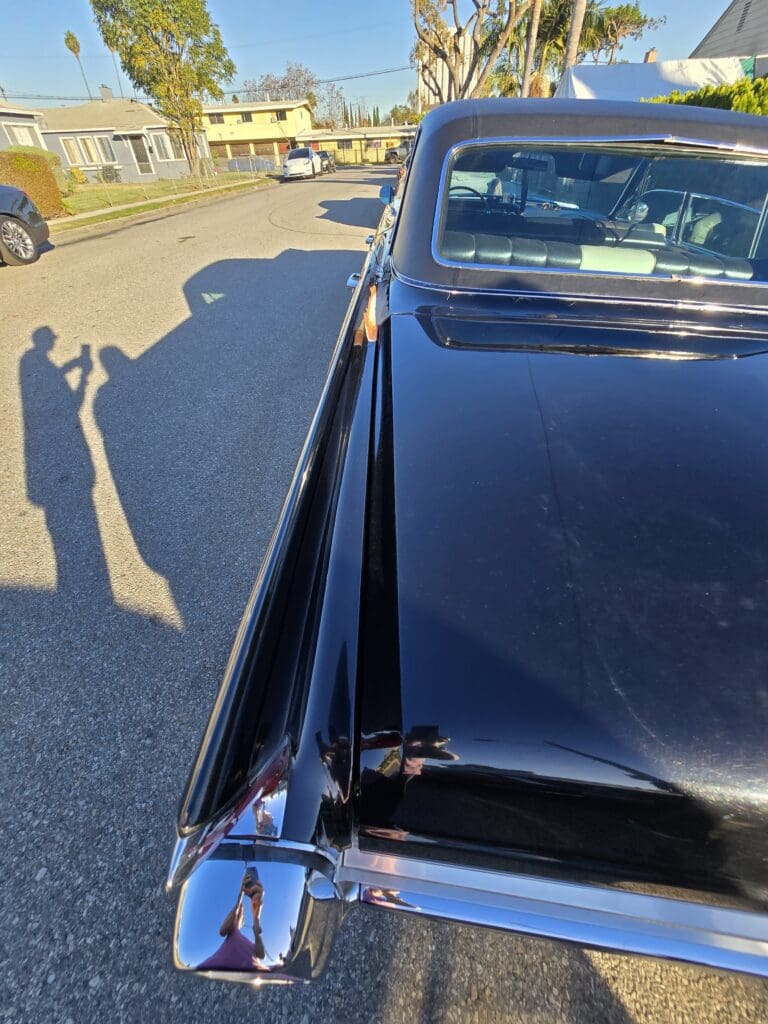 Shadow of a person taking a photo near a shiny black car.