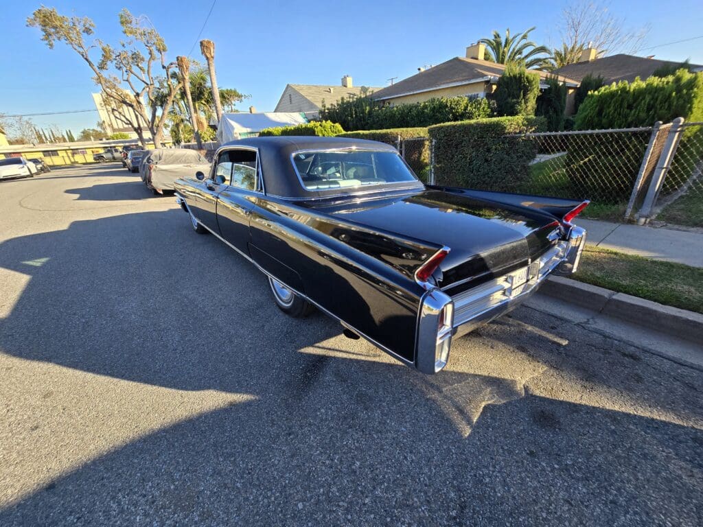 Classic black vintage car parked on a sunny suburban street.