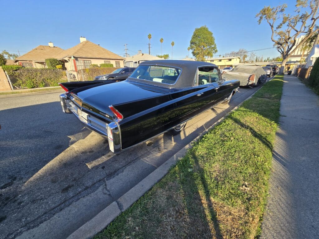 Classic black vintage car parked on a suburban street under clear skies.