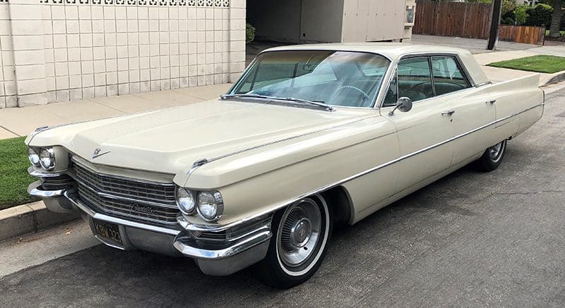 Classic cream-colored Cadillac parked near a tiled wall.