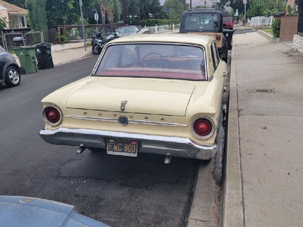 Vintage yellow car parked on a city street.