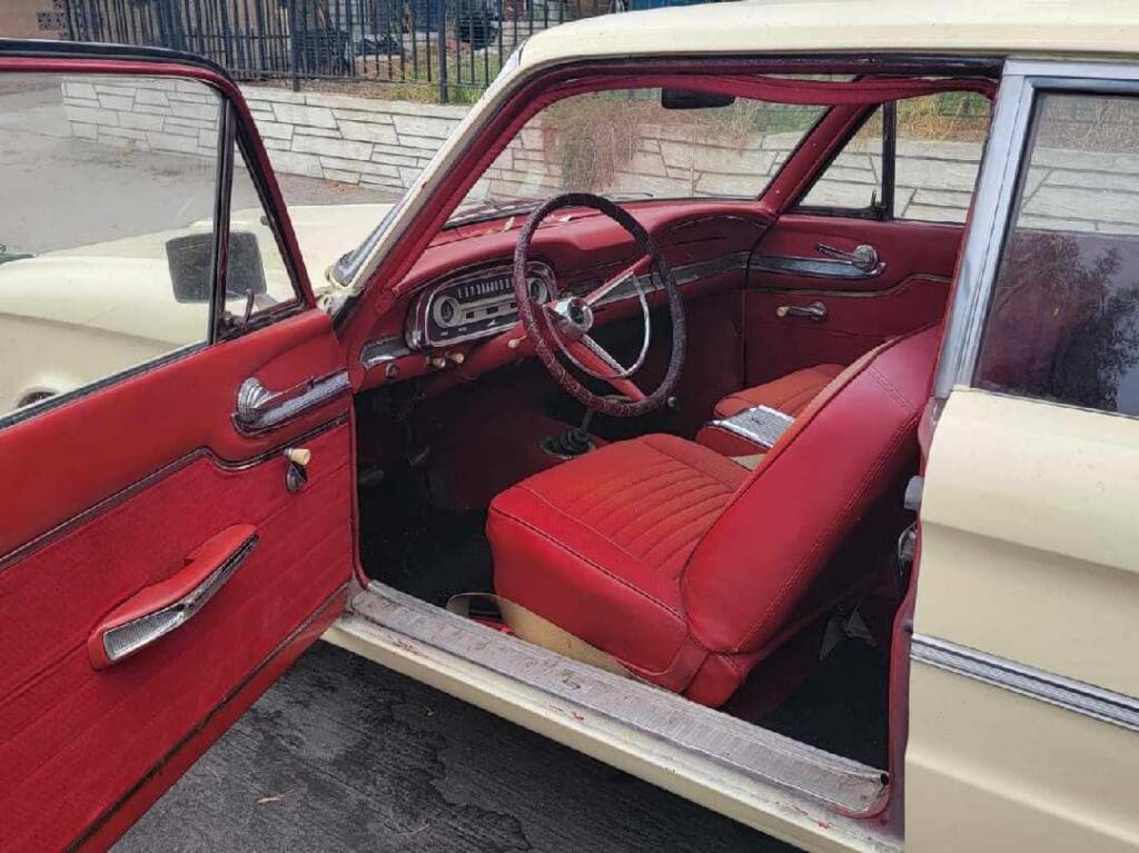 Interior of a vintage car with red seats and dashboard.