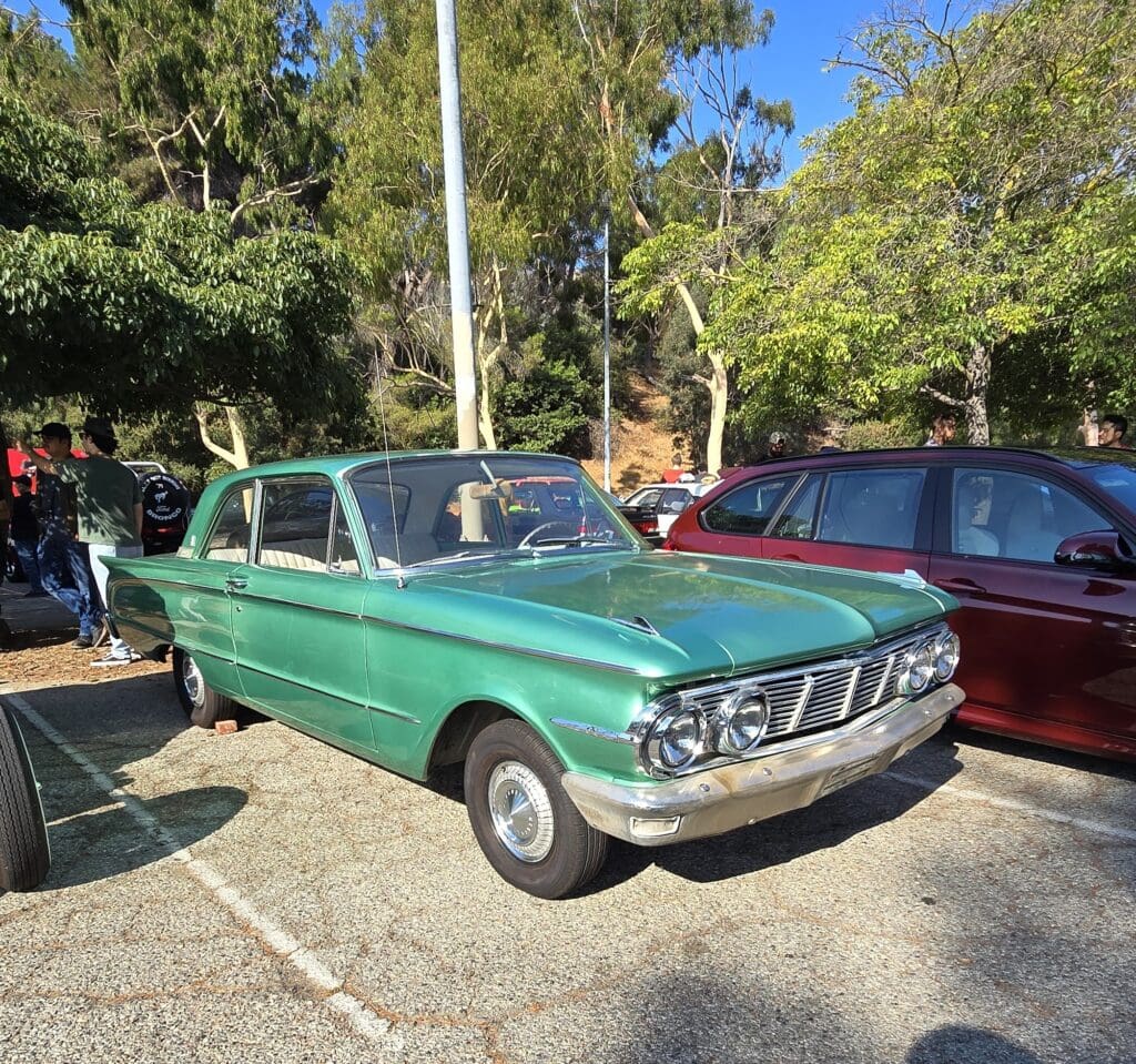 Green classic car parked outdoors on a sunny day.