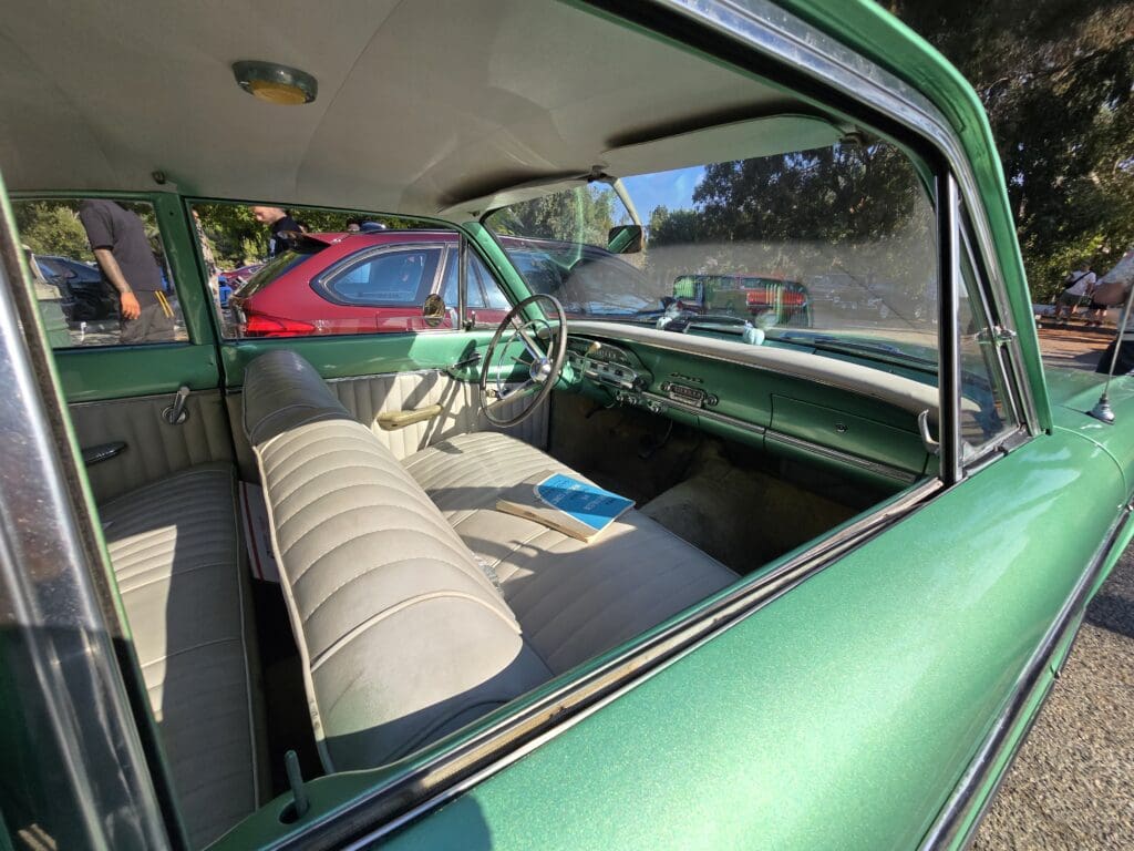 Green classic car parked outdoors on a sunny day.