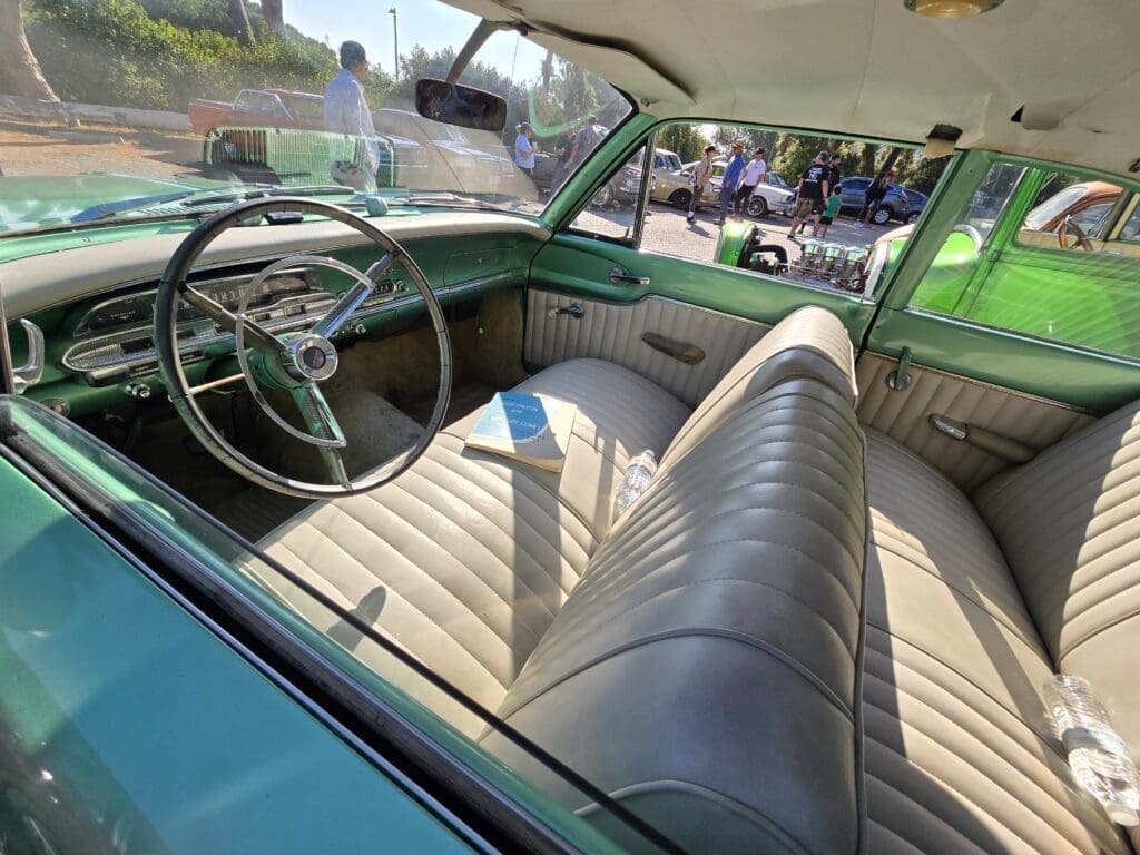 Green classic car parked outdoors on a sunny day.