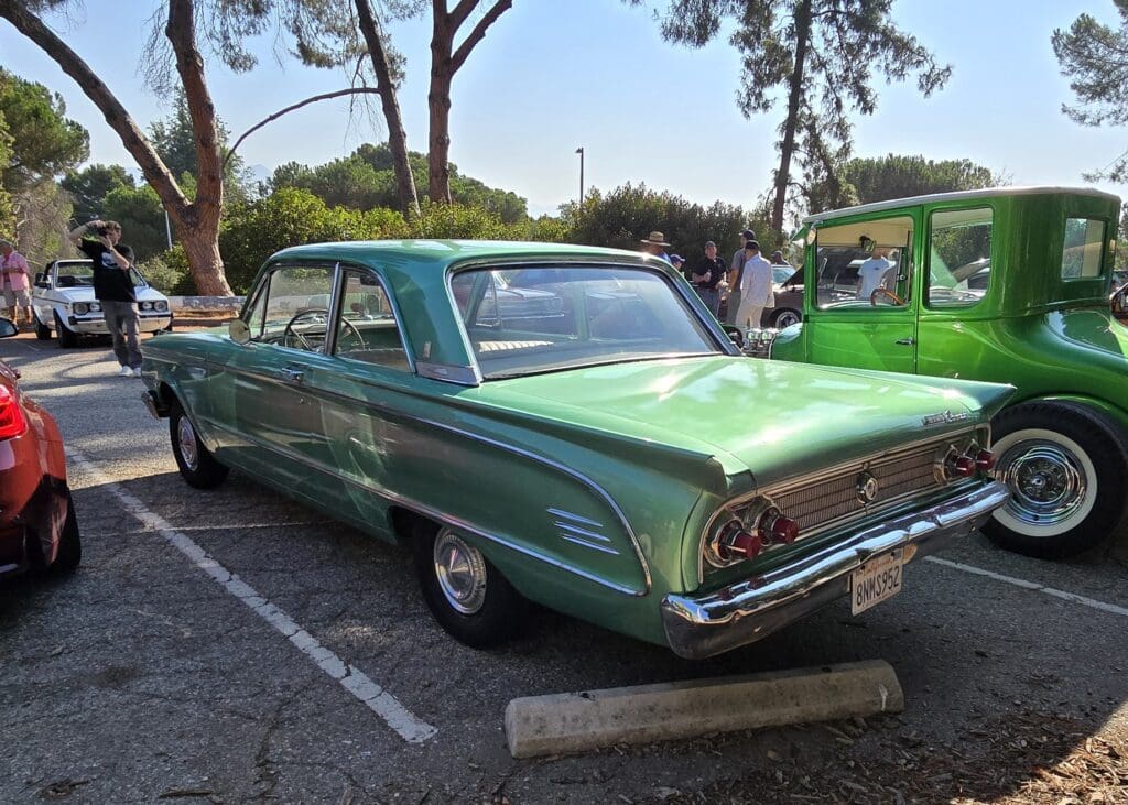 A vintage green car parked outdoors on a sunny day.