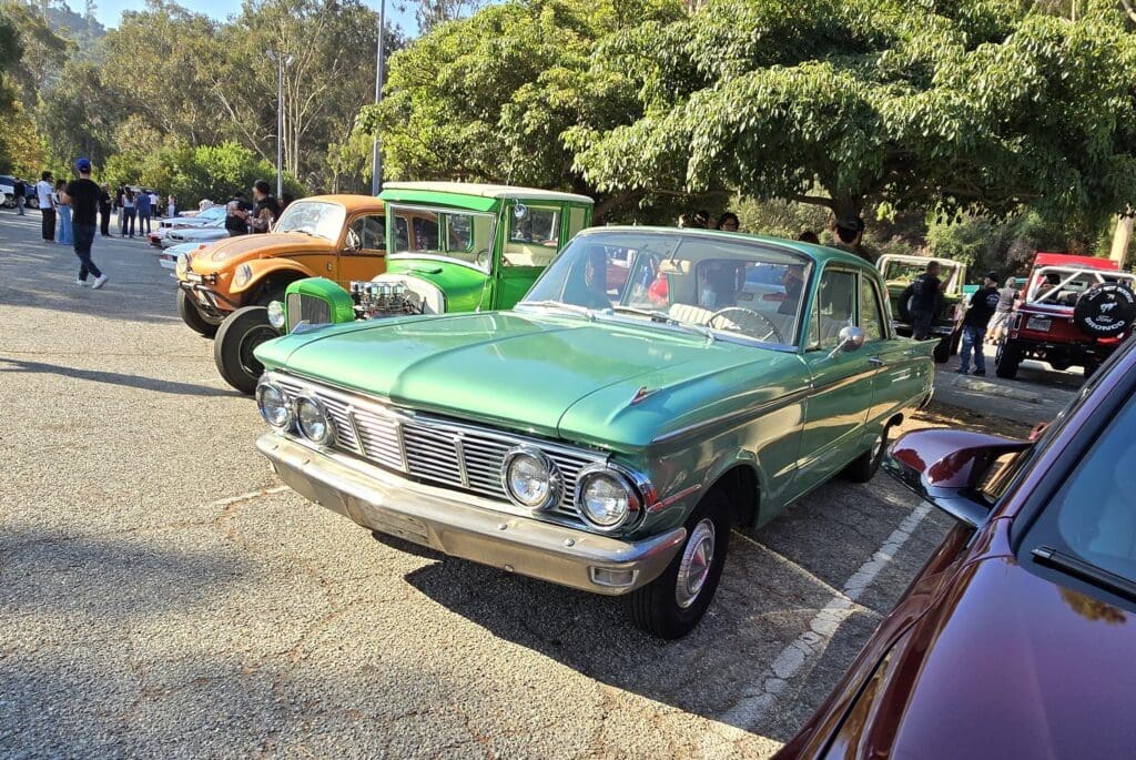 Classic green vintage car parked outdoors on a sunny day.