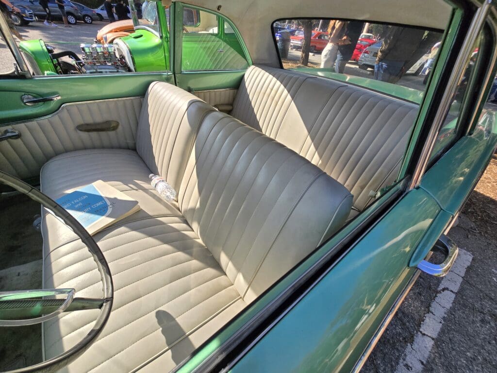 Interior of a classic car with white leather seats and green exterior.