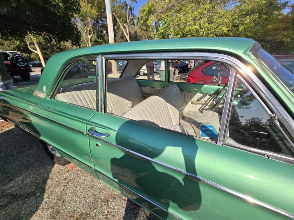 A green vintage car parked outdoors on a sunny day.