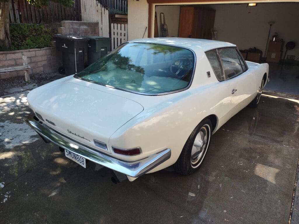 White classic car parked in a driveway beside a house.