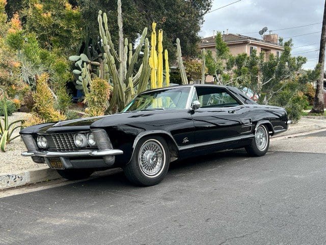 Classic black muscle car parked on a suburban street.