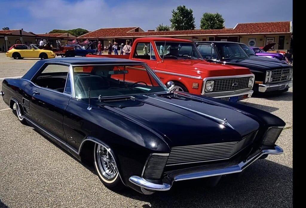Classic black car parked beside a red vintage truck.