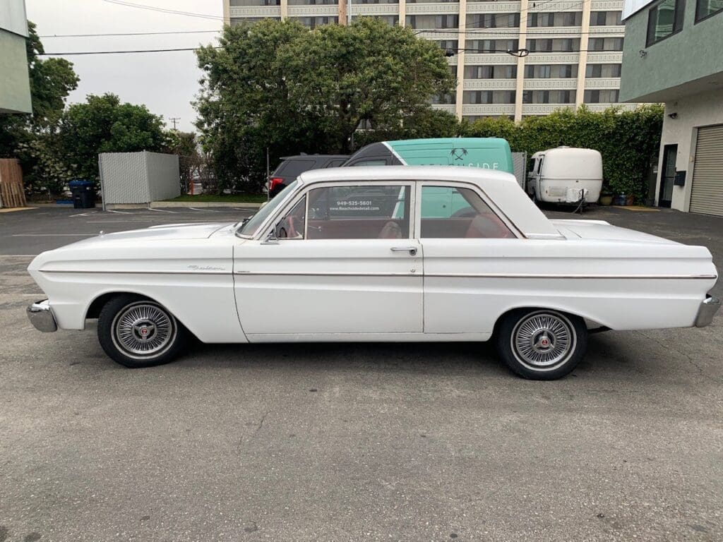 Classic white vintage car parked on the street with a city backdrop.