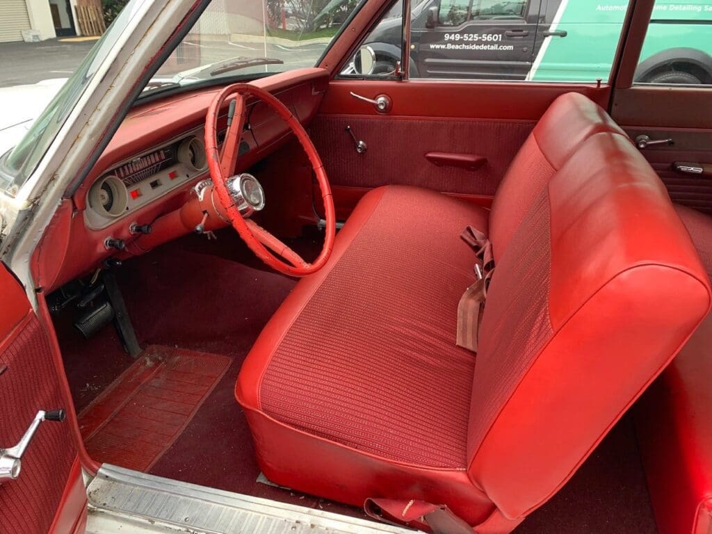 Vintage car interior with vibrant red seats and steering wheel.