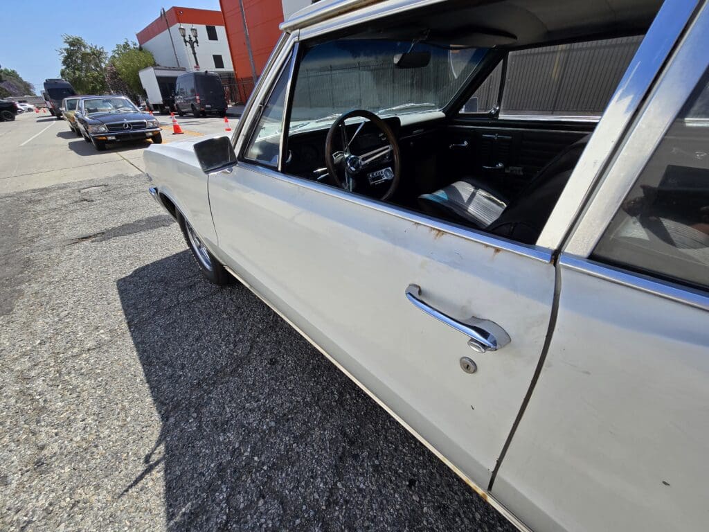 Close-up of a vintage white car door with chrome handle and window.
