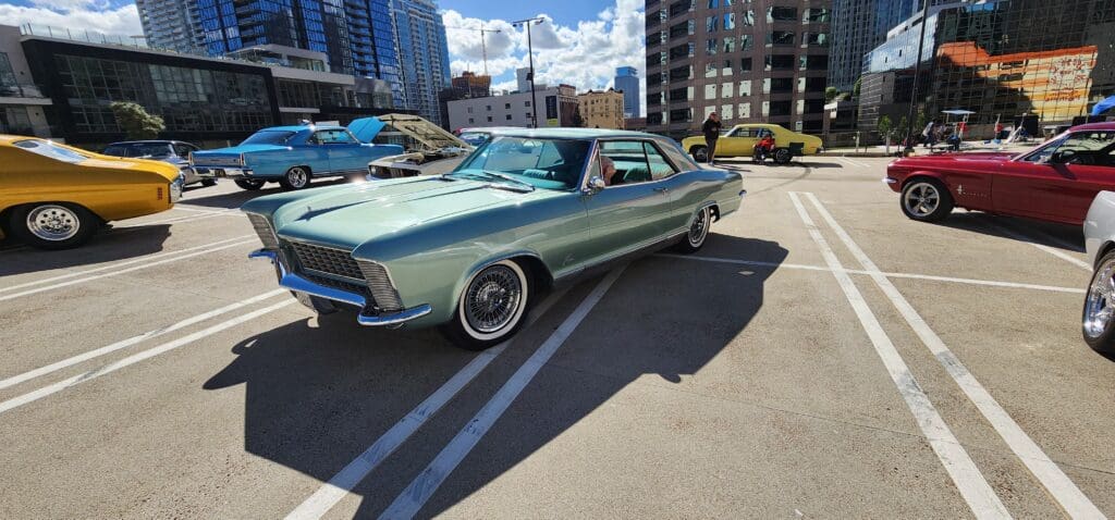 Classic green vintage car parked in a city lot on a sunny day.
