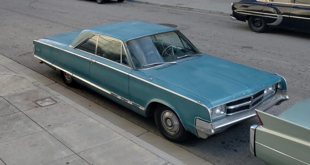 A vintage blue car parked on a street curb with a classic design.