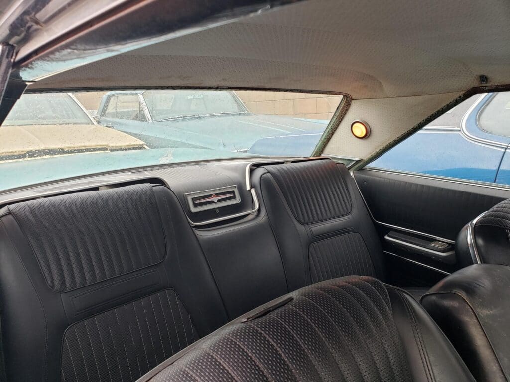 Interior view of a vintage car with black seats and a rear window.