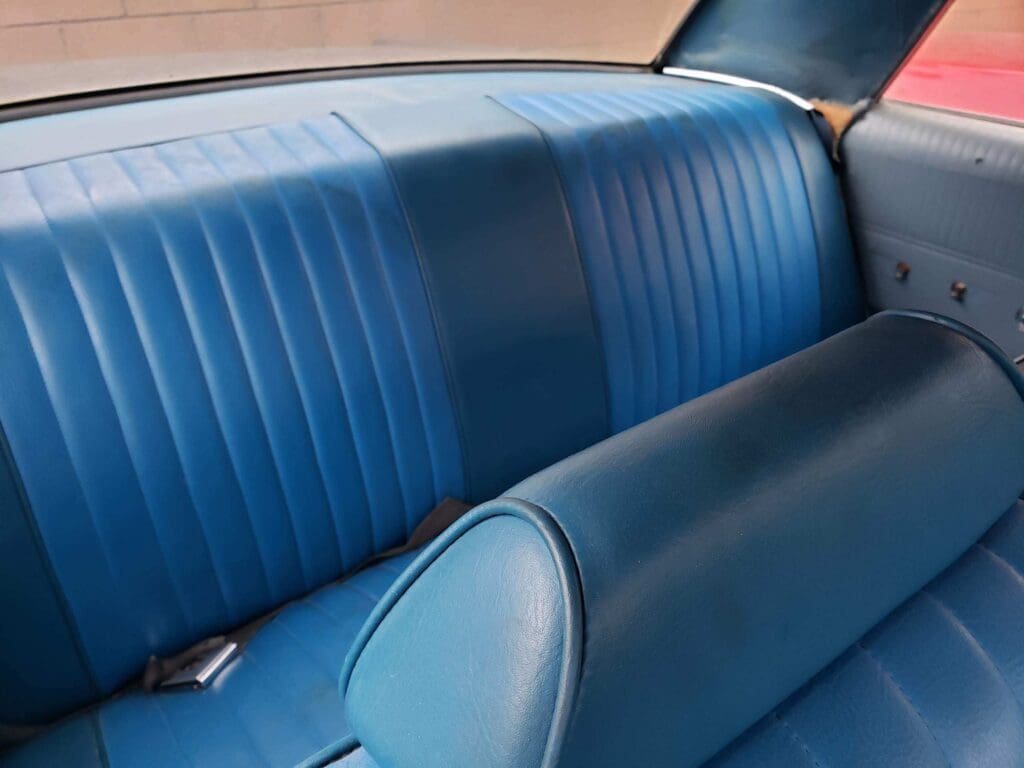 Blue leather car backseat with vertical stitching design.