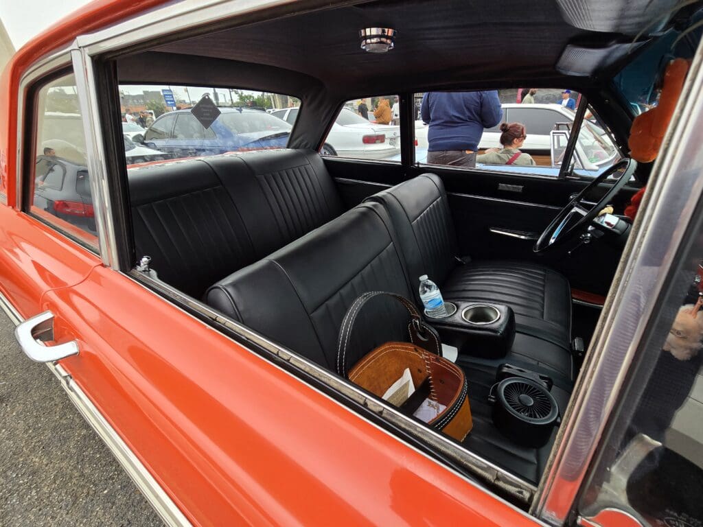 Classic car interior with vintage seats and steering wheel.