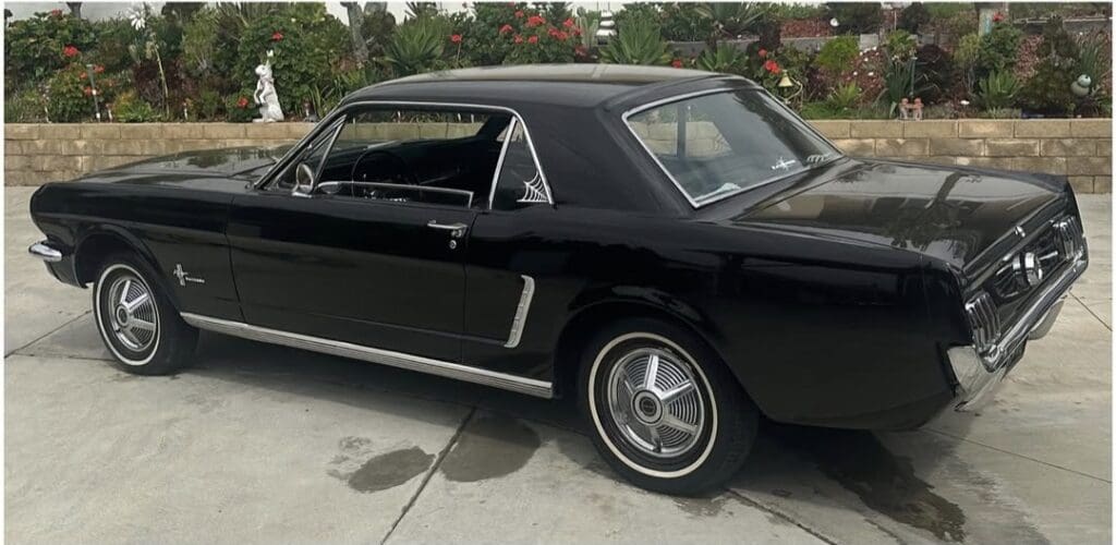 Classic black vintage Ford Mustang parked on a driveway.