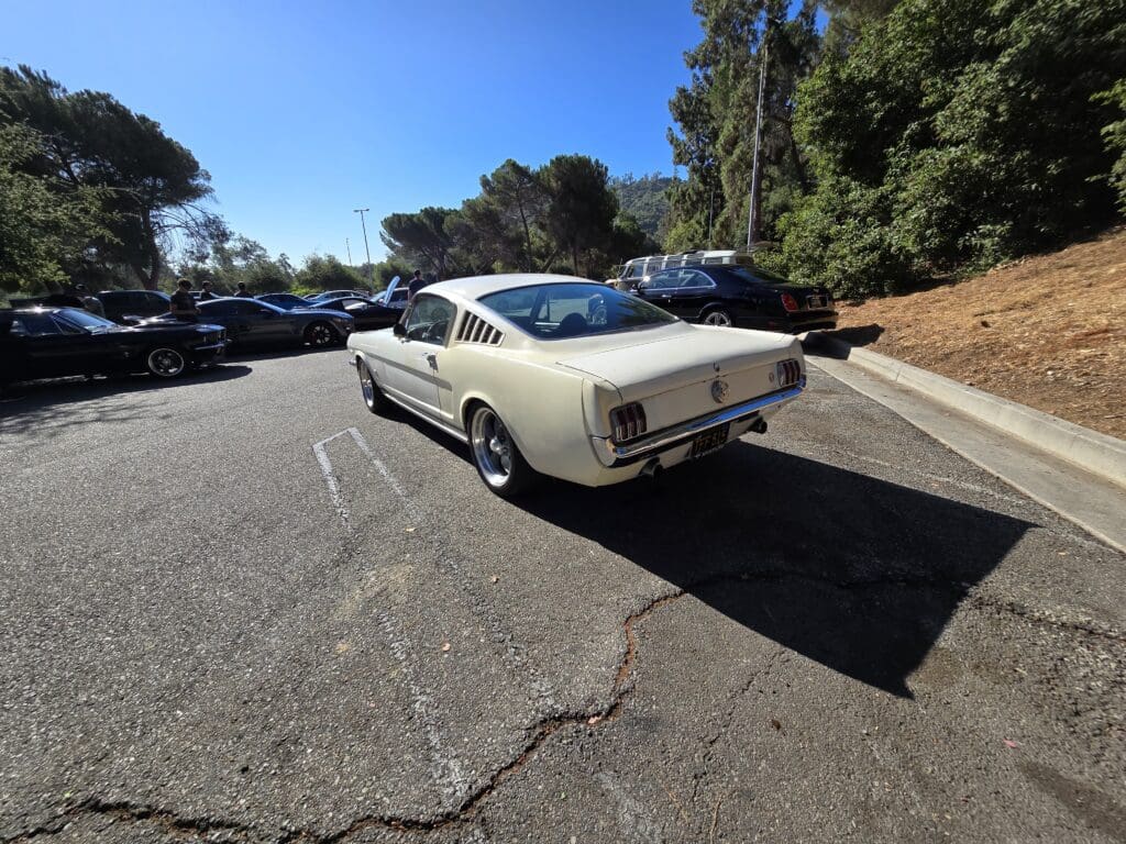 Classic white car parked on a sunny street with trees.