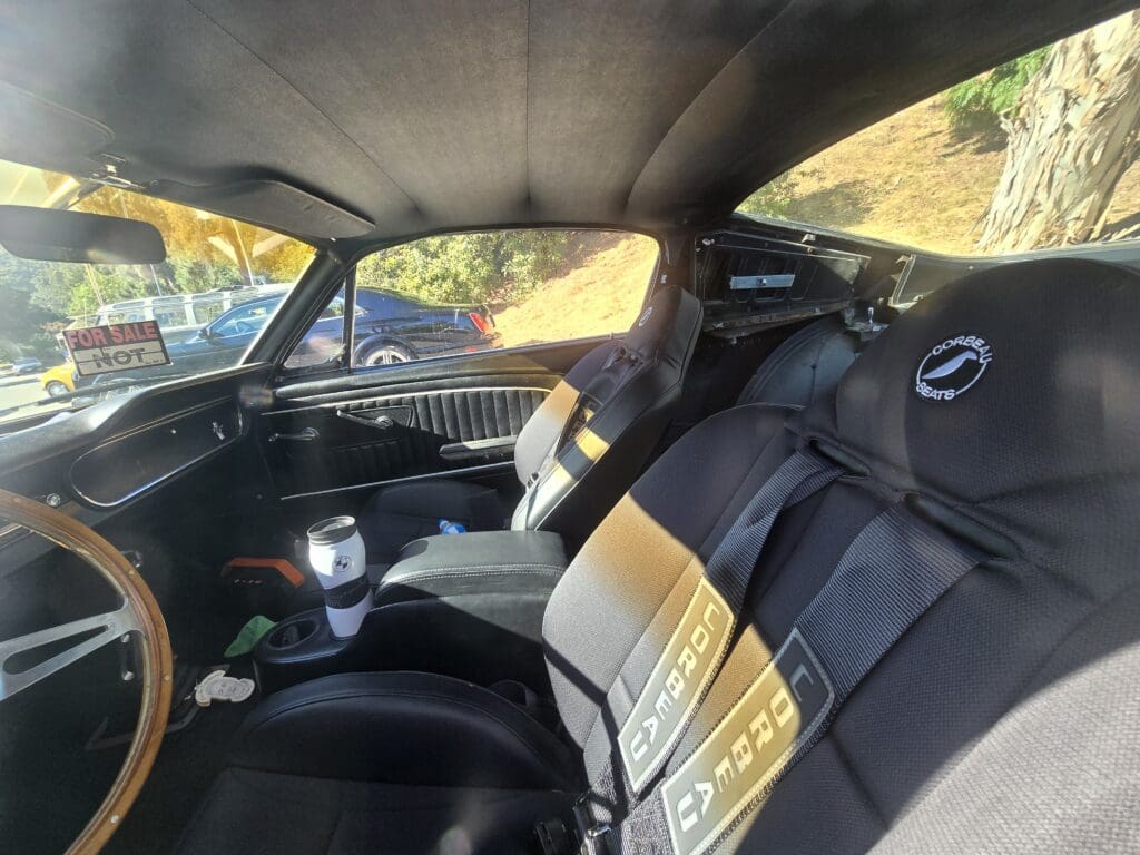 Interior of a car with black and yellow seat covers and a white cup in the cup holder.