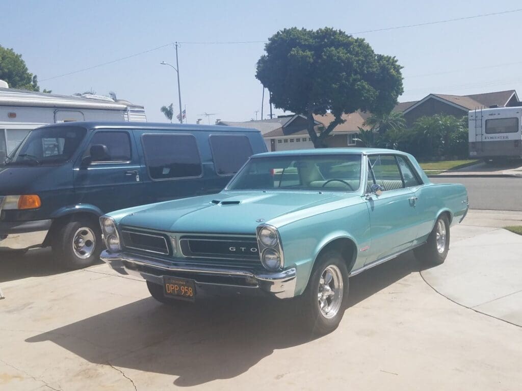 A vintage blue Pontiac GTO parked outdoors on a sunny day.