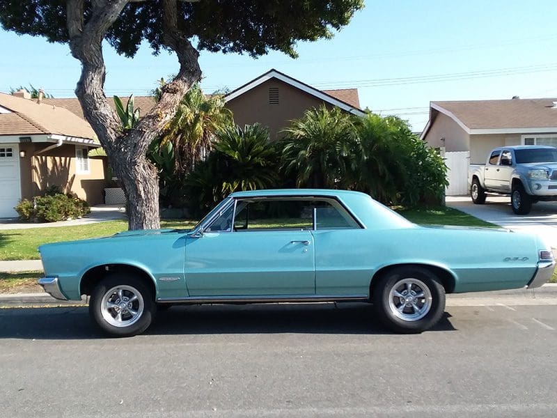 Classic light blue muscle car parked on a suburban street.