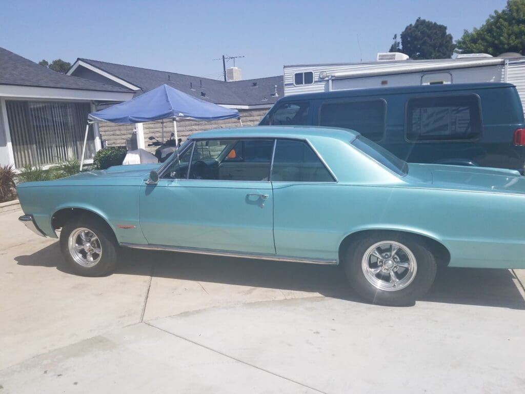 Classic light blue muscle car parked on a suburban street.