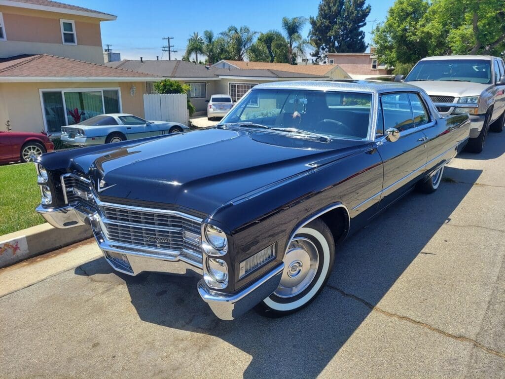 Classic blue and white vintage car parked in driveway under clear sky.