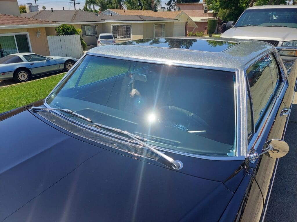 Close-up of a classic car windshield with chrome trim and wipers.
