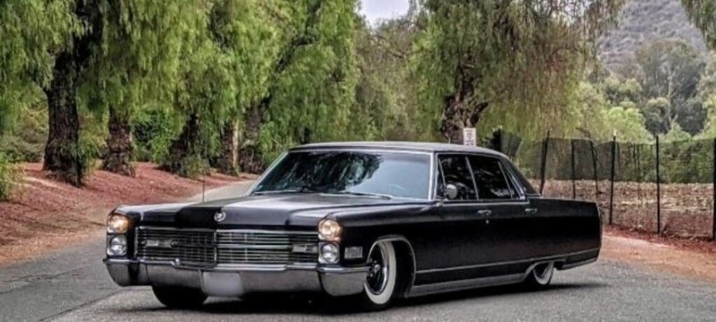 Classic black vintage car parked on a tree-lined street.