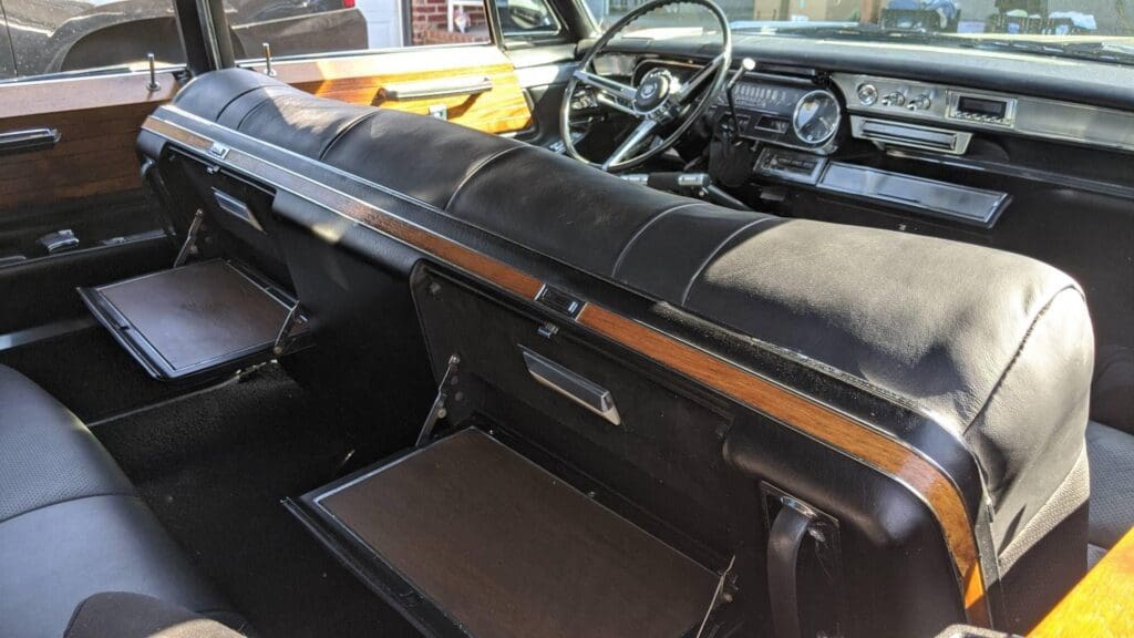 Interior view of a vintage car showing the dashboard and open glove compartment.