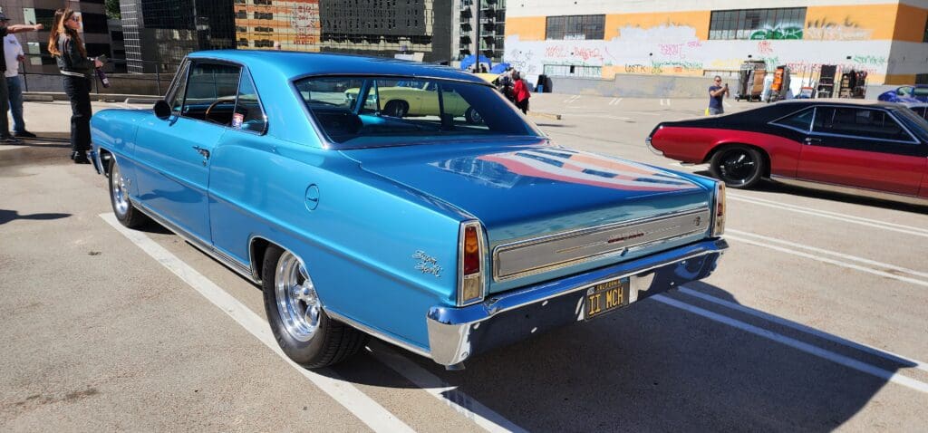 Blue vintage muscle car parked outdoors with shiny chrome accents.