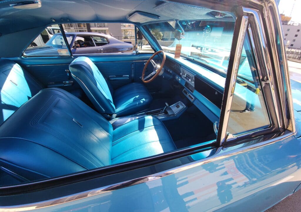 Classic car interior with blue leather seats and vintage steering wheel.