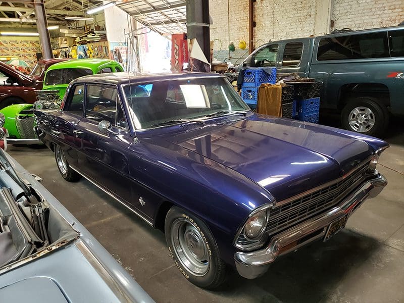 A classic purple vintage car parked indoors.