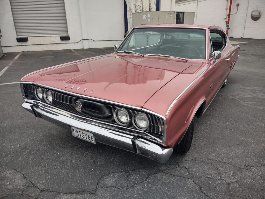 Classic pink 1960s muscle car parked outdoors.