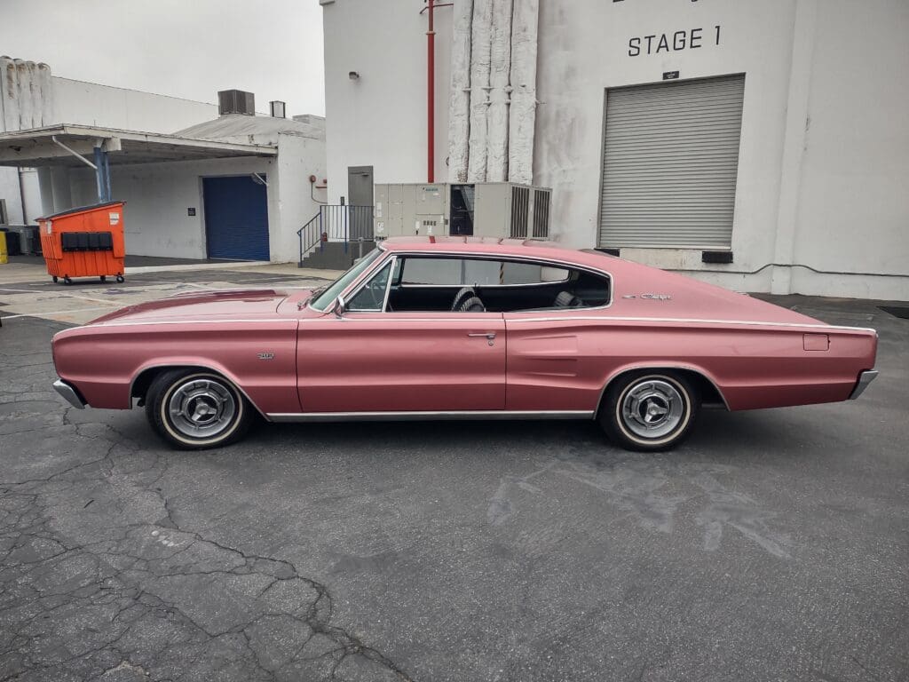 Classic pink muscle car parked in an industrial area.
