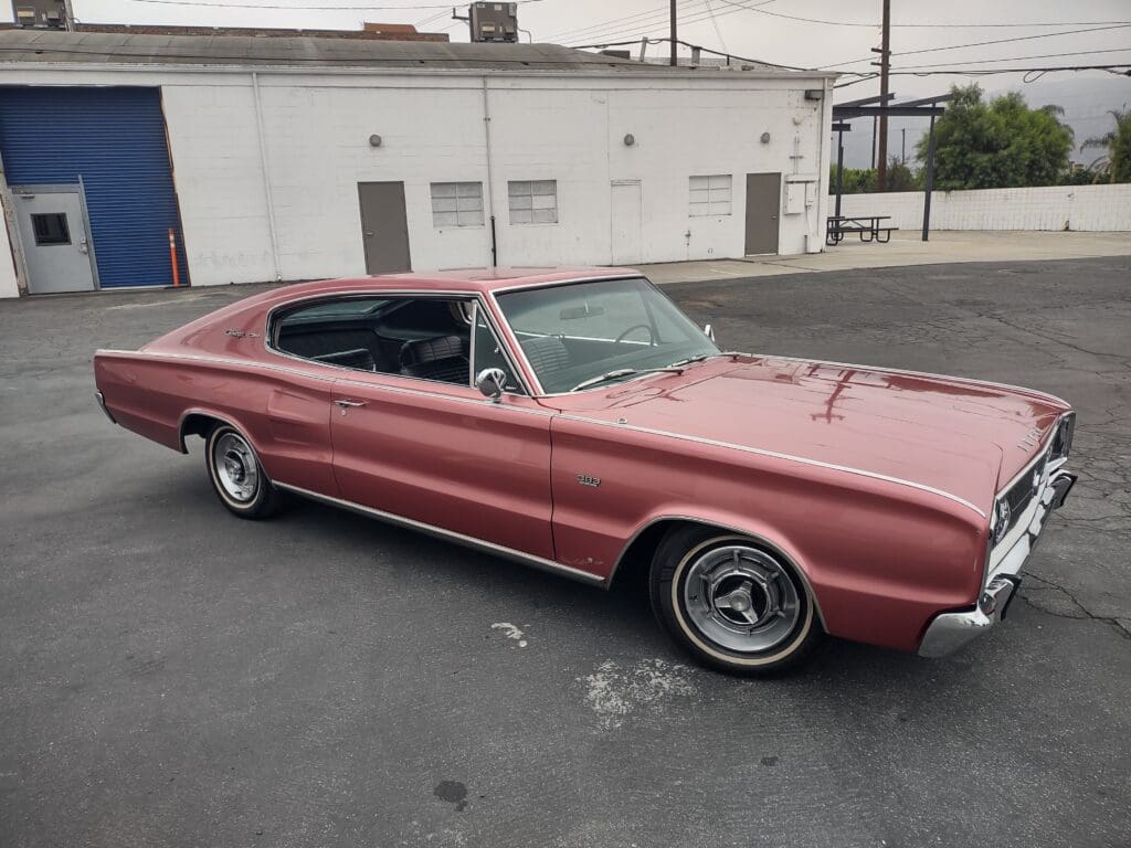Classic red muscle car parked on asphalt near a white building.
