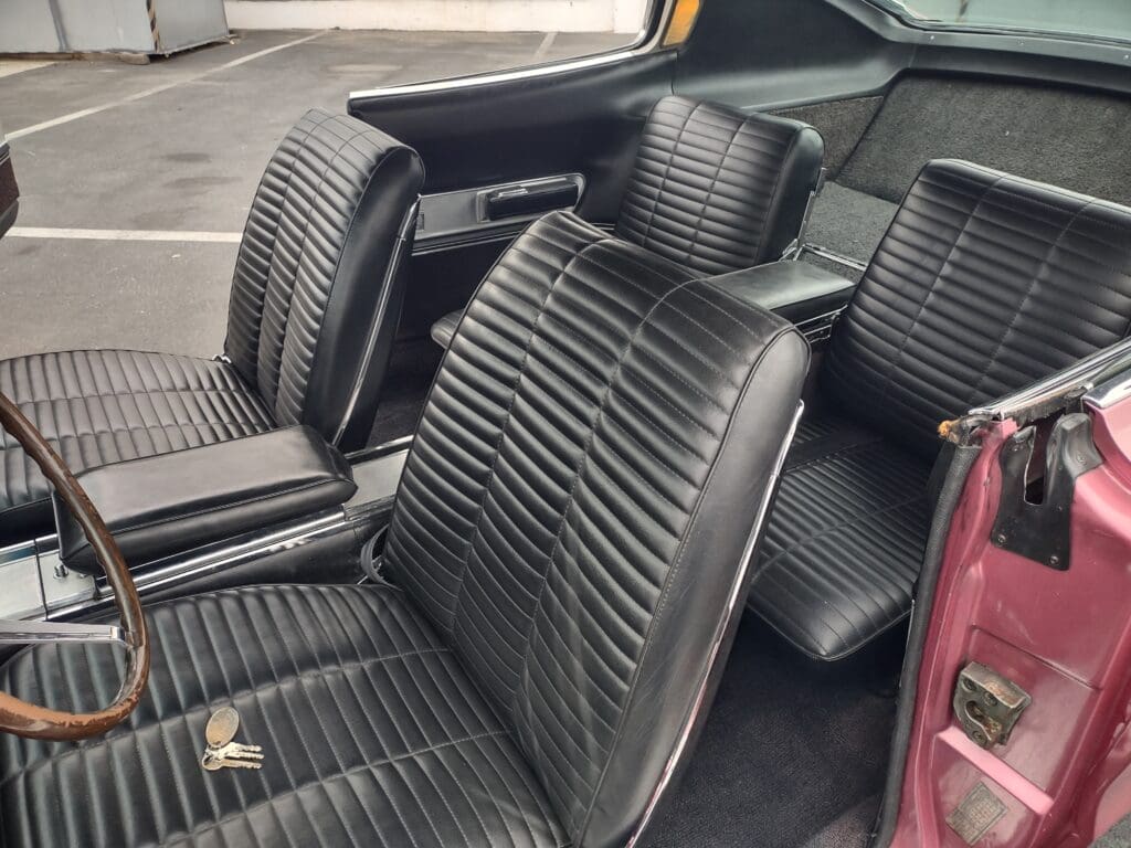 Close-up of vintage car seats with black leather upholstery and ribbed design.