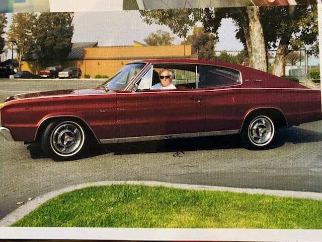 A person driving a classic maroon car on a sunny day.